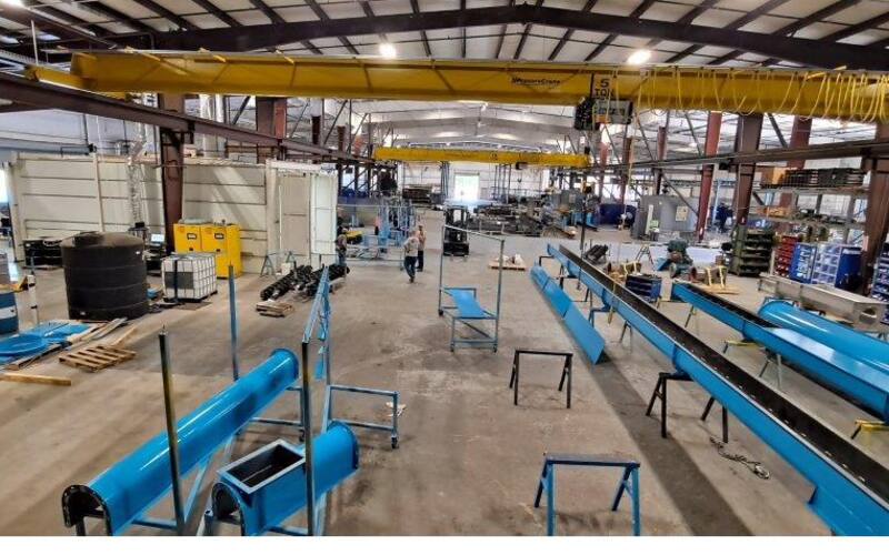 Facility floor with painted screw conveyors and overhead crane