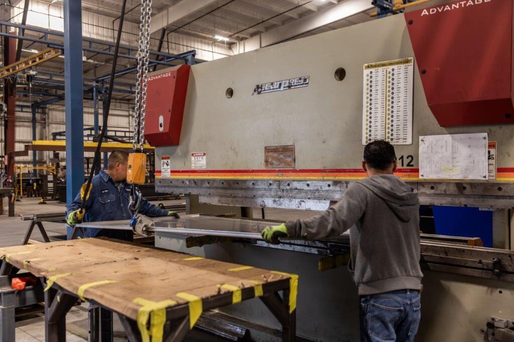 Press brake operators guiding a formed steel panel