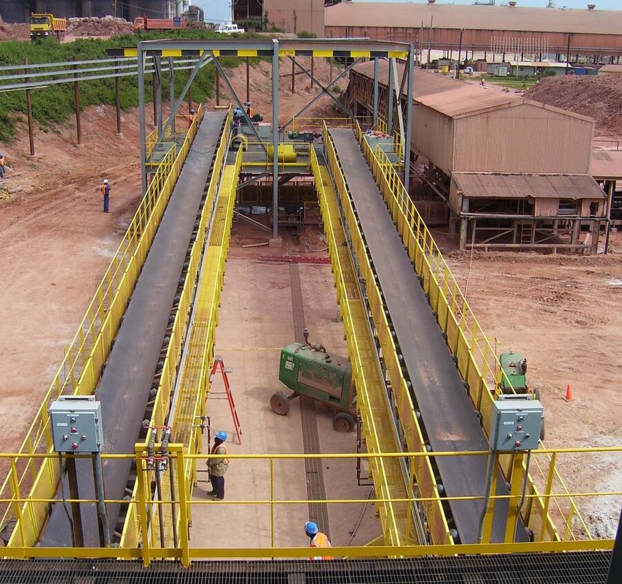 Two parallel troughed belt conveyors with walkways and safety handrails at a bulk material plant