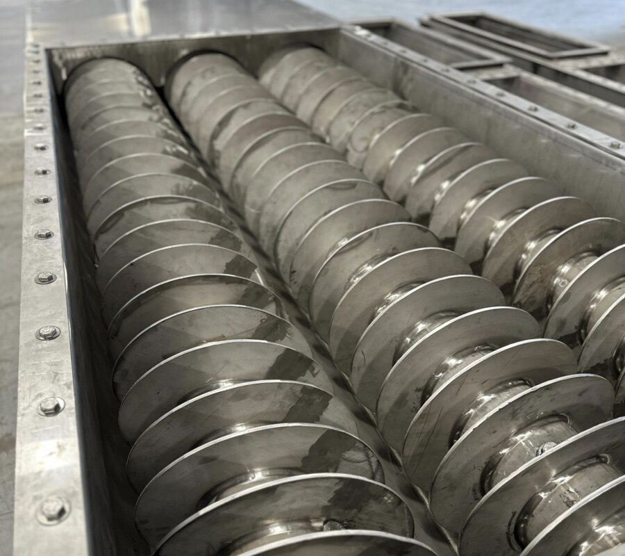 Three-screw live bottom feeder, screws set in the stainless trough on the shop floor at Orthman Conveying Systems